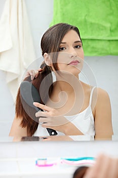 Beautiful young woman brushing her hair