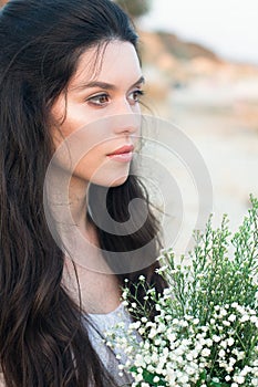 Beautiful young woman with bunch of wildflowers