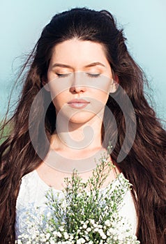 Beautiful young woman with bunch of wildflowers