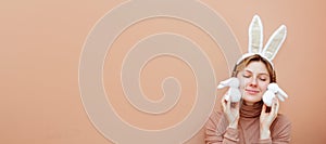 Beautiful young woman with bunny ears on pink background. Handmade Easter decoration. Horizontal banner with copy space