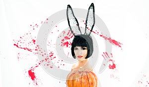 Beautiful young woman in bunny ears with pumpkin. Bloody halloween. Sexy woman bunny rabbit. Girl with pumpkin. Happy