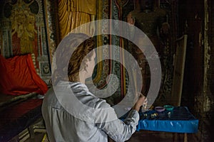 Beautiful young woman burning incense sticks in the buddhist temple