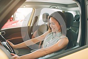 Beautiful young woman buying a car at dealership. Female model sitting Sits in the car interior