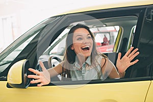 Beautiful young woman buying a car at dealership. Female model sitting Sits in the car interior