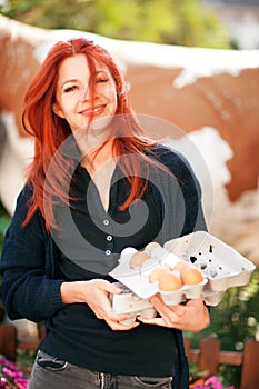 Beautiful young woman buying fresh eggs at a farm