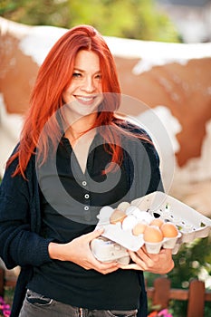 Beautiful young woman buying fresh eggs at a farm