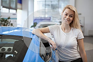 Beautiful young woman buying new car at the dealership