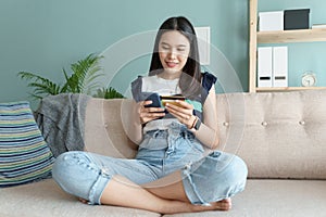 Beautiful of young woman are buying online with a credit card while sitting on the sofa in the living room. Women are using