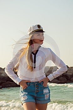 Beautiful young woman in a captain hat at the beach