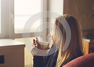 Beautiful young woman in casual wear dreaming with cup of coffee