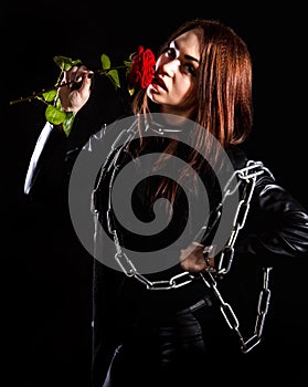 Beautiful young woman with chains and a red rose