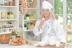 Beautiful young woman in chefs hat baking at home