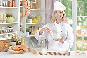 Beautiful young woman in chefs hat baking at home