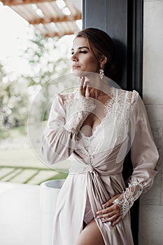 Beautiful young woman in a chic pink bathrobe spends time alone in an expensive hotel in the summer during the holidays