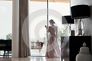 Beautiful young woman in a chic pink bathrobe spends time alone in an expensive hotel in the summer during the holidays