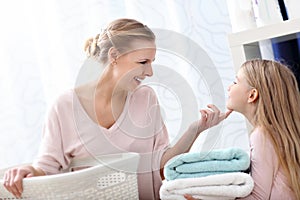 Beautiful young woman and child girl having fun while doing laundry at home
