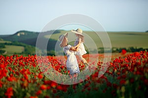 Beautiful young woman with child girl in poppy field. happy family having fun in nature. outdoor portrait in poppies