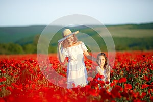 Beautiful young woman with child girl in poppy field. happy family having fun in nature. outdoor portrait in poppies