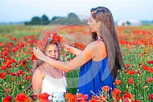 elegant young woman with child girl in poppy field, happy family having fun in nature, summer time