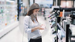 Beautiful young woman chooses makeup bag in cosmetics shop