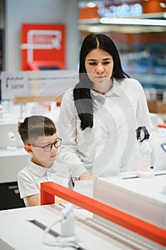 Beautiful young woman choosing which smart phone to buy. Shopping in tech store.