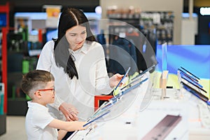 Beautiful young woman choosing which smart phone to buy. Shopping in tech store.