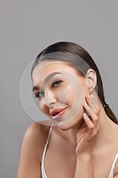Beautiful young woman with clean face. Portrait of beauty model with clean perfect skin touching her face