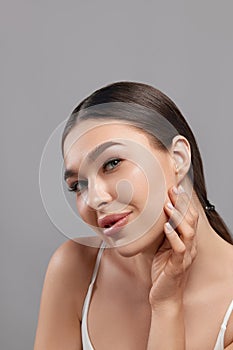 Beautiful young woman with clean face. Portrait of beauty model with clean perfect skin touching her face. Spa, skin care and well