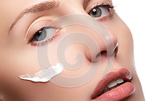 Beautiful young woman with clean fresh skin close-up. Beautiful woman face close up studio on white. Young woman with cosmetic cre