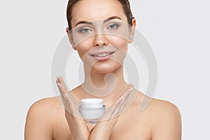 Beautiful young woman with clean fresh skin. Girl holding cream in her hand
