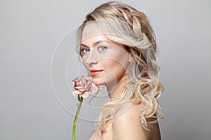 Beautiful young woman with clean fresh skin touch her face flower. Facial treatment. Cosmetology, beauty and spa