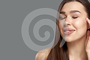 Beautiful young woman with clean perfect skin. Portrait of beauty model with natural nude make up and touching her face.