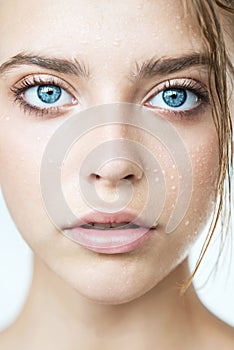 Beautiful young woman with clean perfect skin and water moisture drops touching face