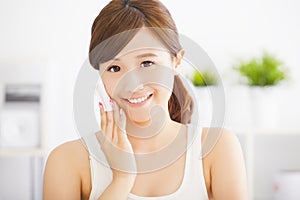 Beautiful young woman cleaning her face with cotton