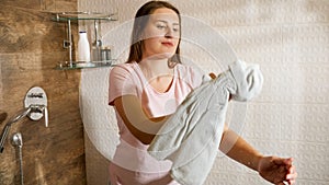 Beautiful young woman cleaning and wiping glass door in the shower at hotel room.