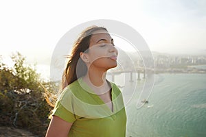 Beautiful young woman with closed eyes breathing with wind on her face relaxing enjoying sun at sunset. Beauty sunshine girl side