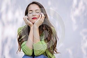 Beautiful young woman with closed eyes daydreaming at the sunglight