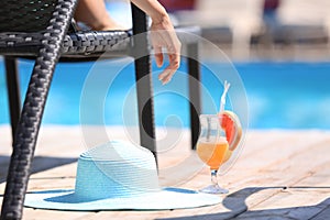 Beautiful young woman with cocktail resting on sun lounger at resort, closeup