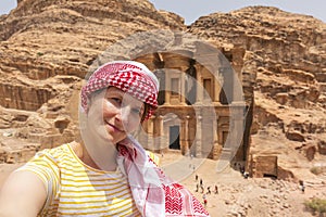 Beautiful young woman in colorful dress and kefiah enjoying at The Monastery, Petra`s largest monument, UNESCO World Heritage Sit