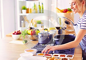 Beautiful young woman cooking in kitchen at home