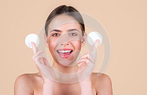 Beautiful young woman with cotton pad removing makeup. Skin care. Studio portrait of girl cleaning her face with cotton