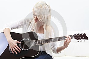 Beautiful young woman on the couch with a guitar photo