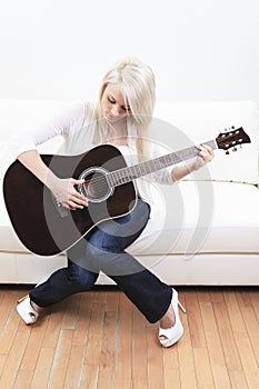 Beautiful young woman on the couch with a guitar photo