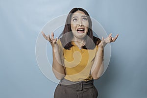Beautiful young woman crying feeling very depressed  by blue background shouting loud