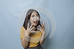 Beautiful young woman crying feeling very depressed  by blue background shouting loud