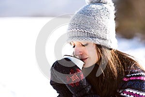 Beautiful young woman with cup of coffee in winter nature