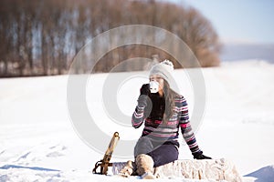 Beautiful young woman with cup of coffee in winter nature