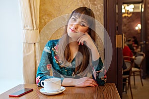 Beautiful young woman with a cup of tea at a cafe