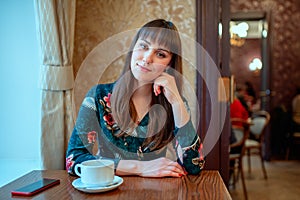 Beautiful young woman with a cup of tea at a cafe