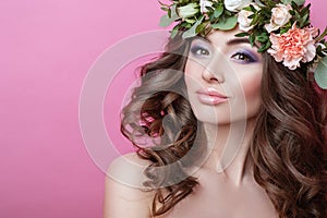 Beautiful young woman with curly hair and flower wreath on her head on pink background Beauty girl with flowers hairstyle Perfect